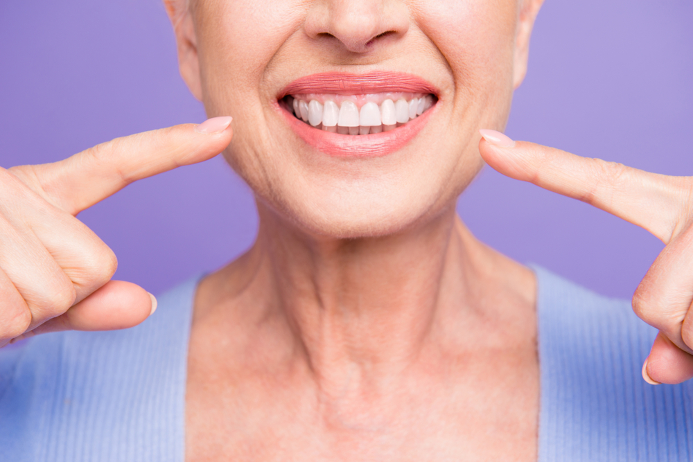 A woman smiling at her teeth after receiving Teeth Whitening