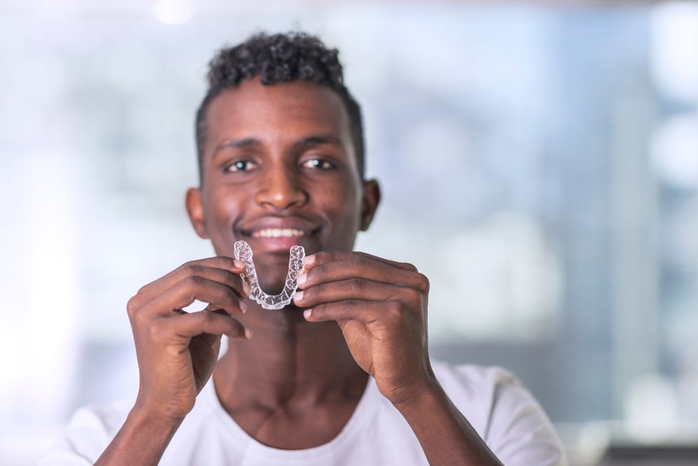 Handsome Young Man Is Holding An Invisaligner