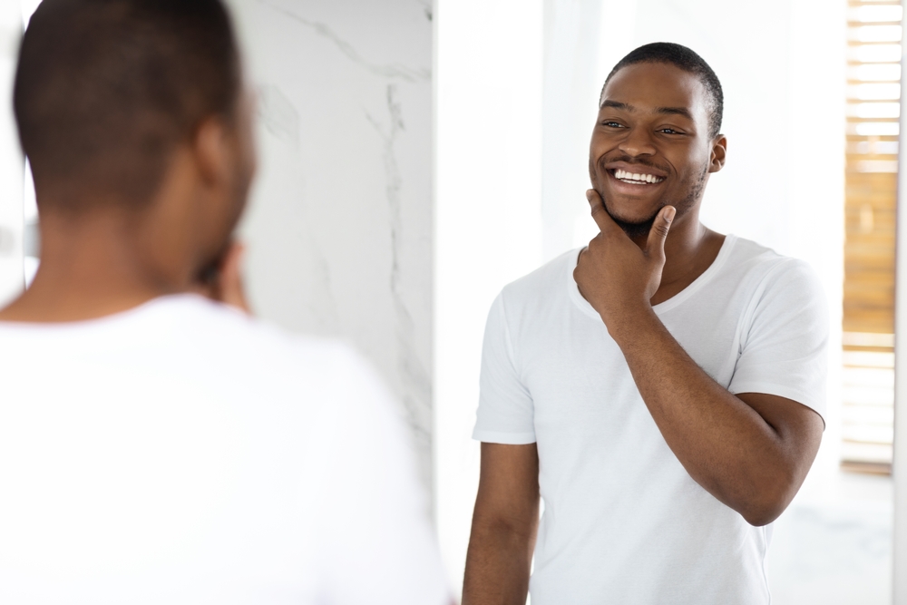 Man smiling in the mirror after receiving Orthodontic Care