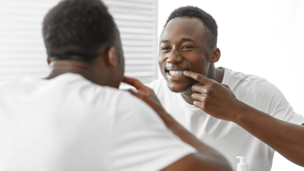 Man smiling in the mirror happy about his teeth